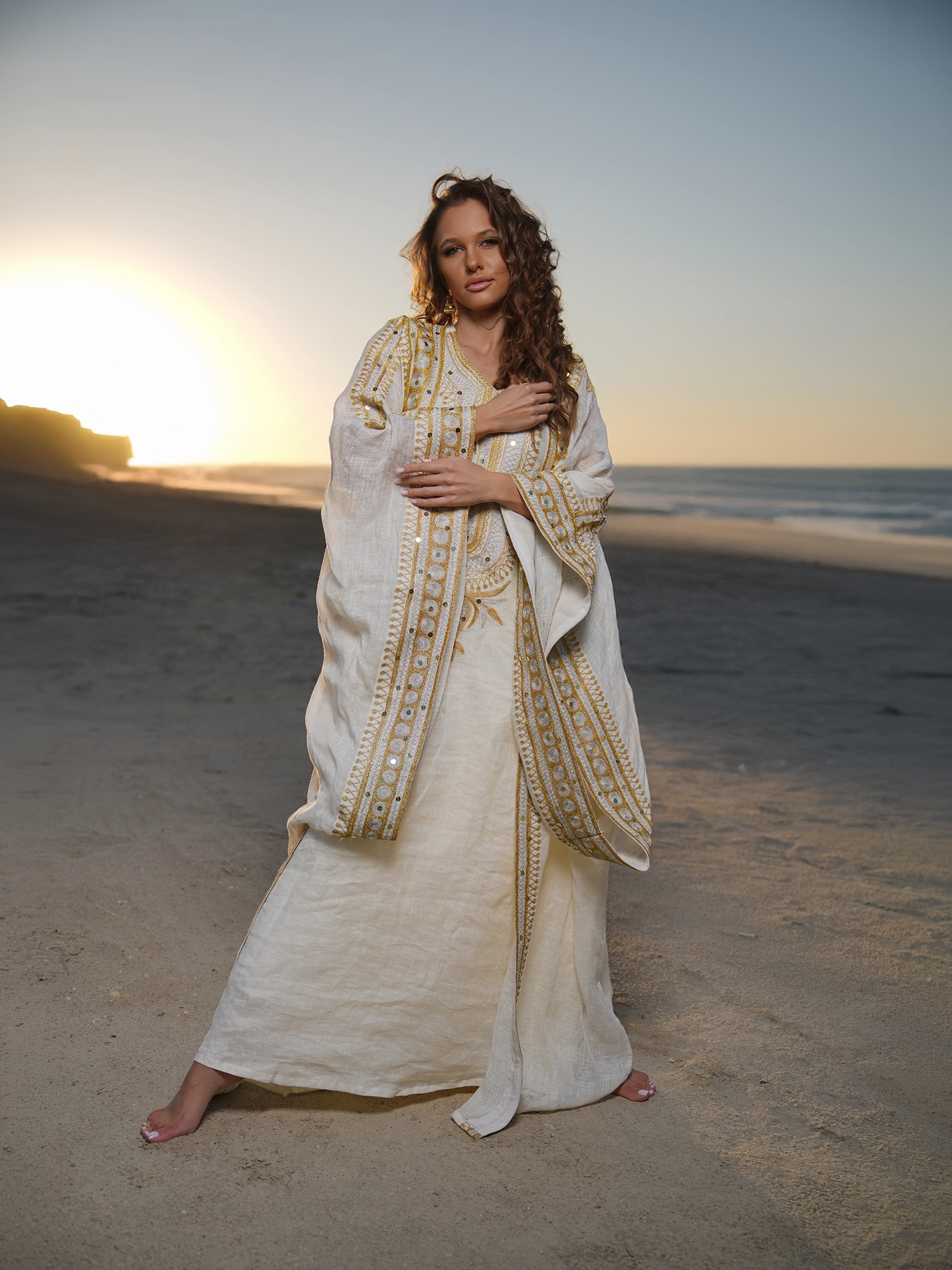 1. Model in embroidered turquoise kaftan photographed in desert at sunset in Kuwait