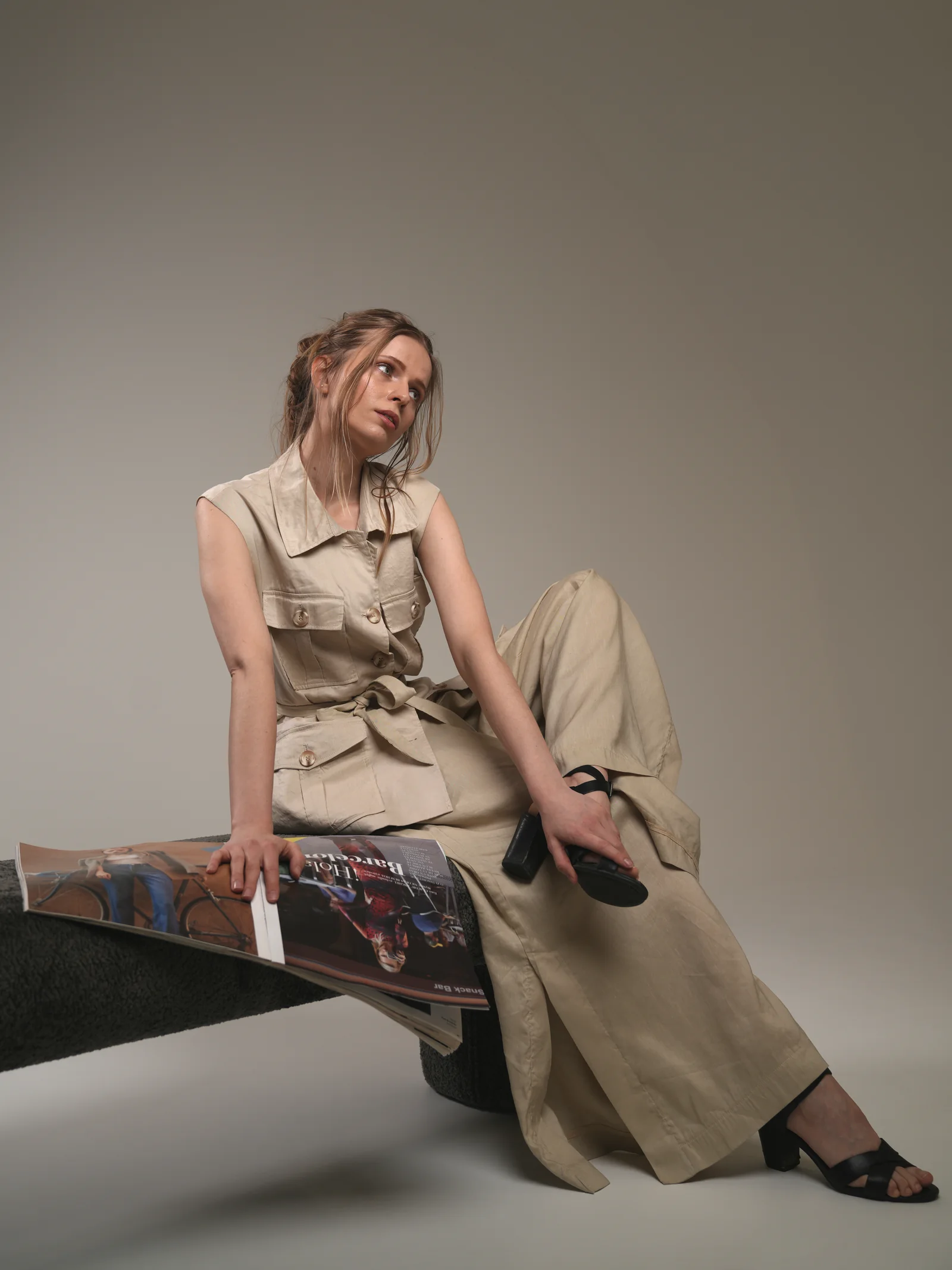 Model in linen safari set seated with magazine, editorial Kuwait