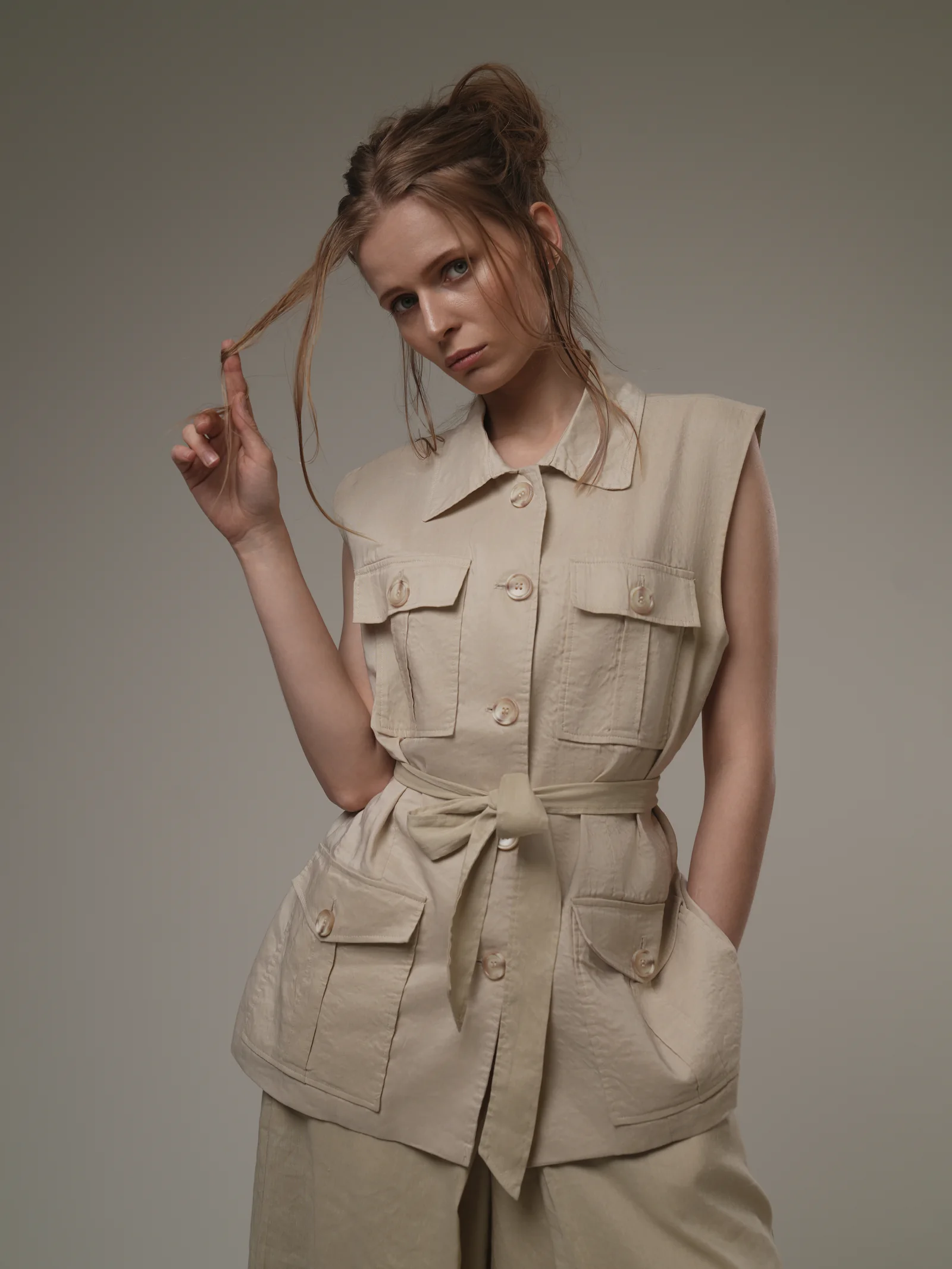 Model in linen safari vest playing with hair, studio portrait Kuwait