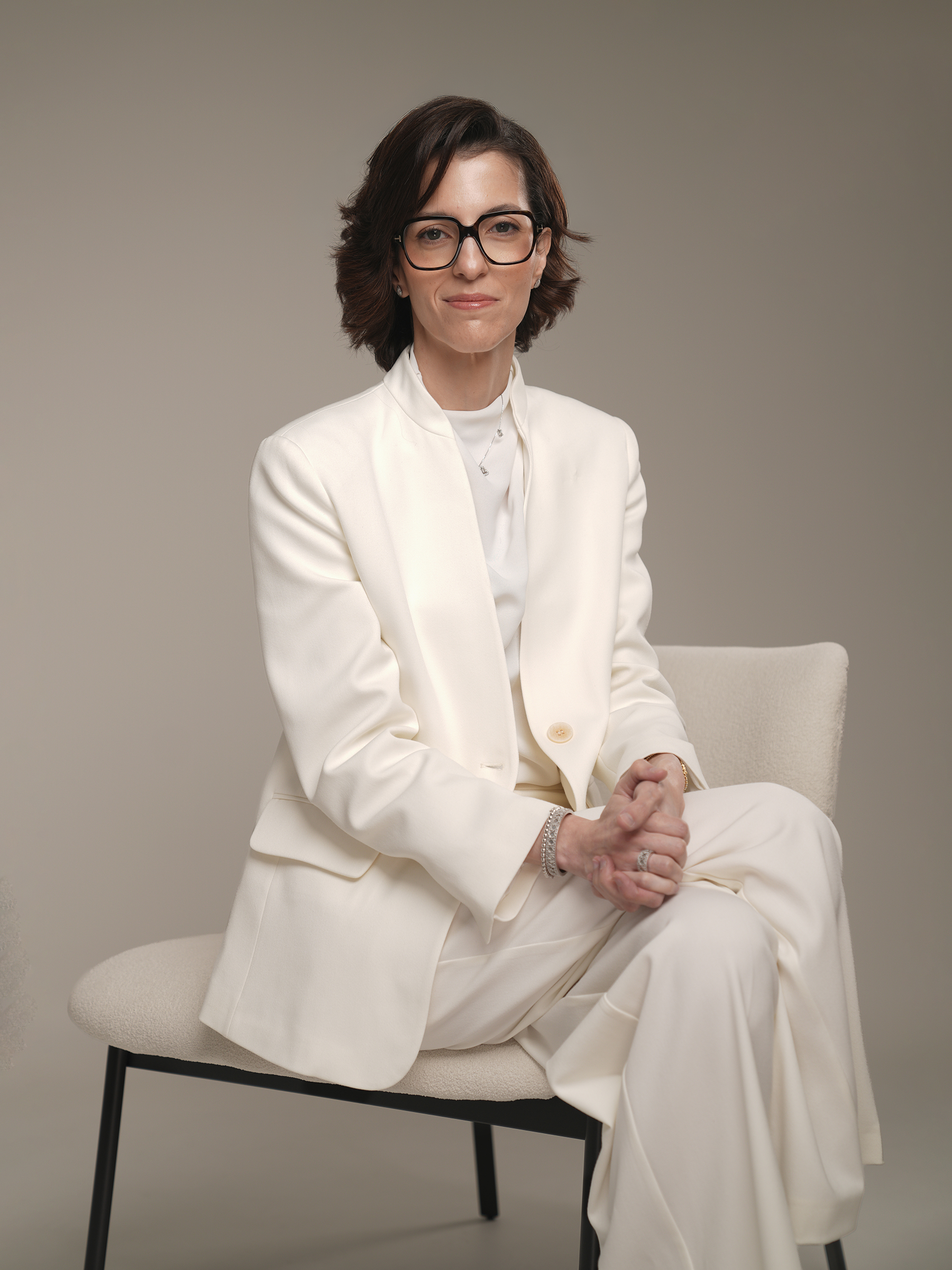 Seated personal branding portrait in an ivory suit on a neutral studio backdrop, Kuwait